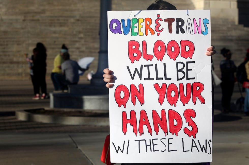 FILE - A protester outside the Kansas Statehouse holds a sign after a rally for transgender...