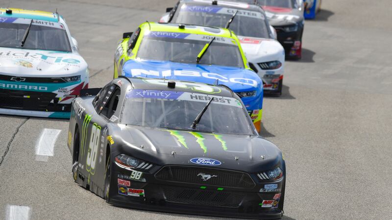 Riley Herbst (98) runs in third place while a group of cars follow close behind during a...