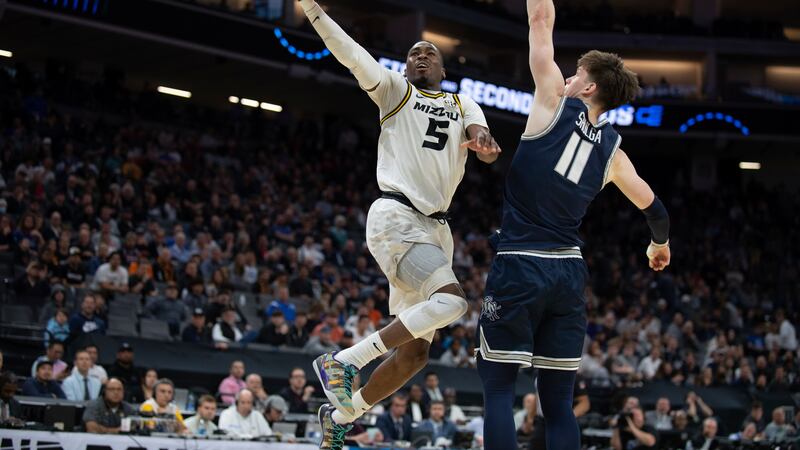Missouri guard D'Moi Hodge (5) scores past Utah State guard Max Shulga (11) during the first...